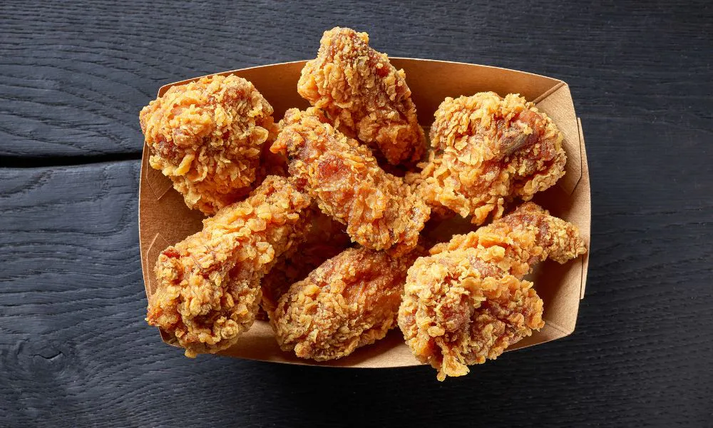 Crispy fried chicken wings in a brown paper tray at Acbento, a Fast Food Restaurant in Flushing