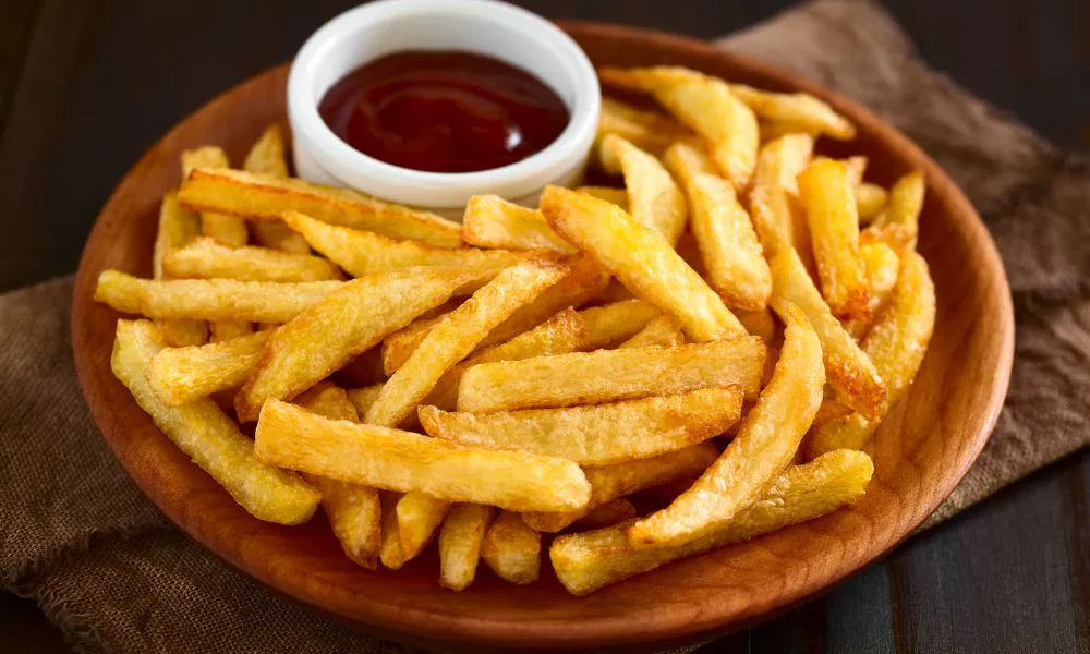 Golden french fries served with ketchup on a wooden plate at Acbento, a Fast Food Restaurant in Flushing