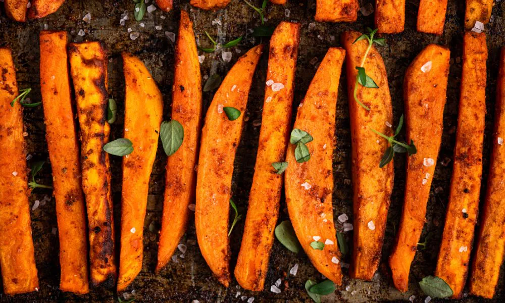 Roasted sweet potato wedges with herbs and sea salt on a baking sheet at Acbento, a Fast Food Restaurant in Flushing